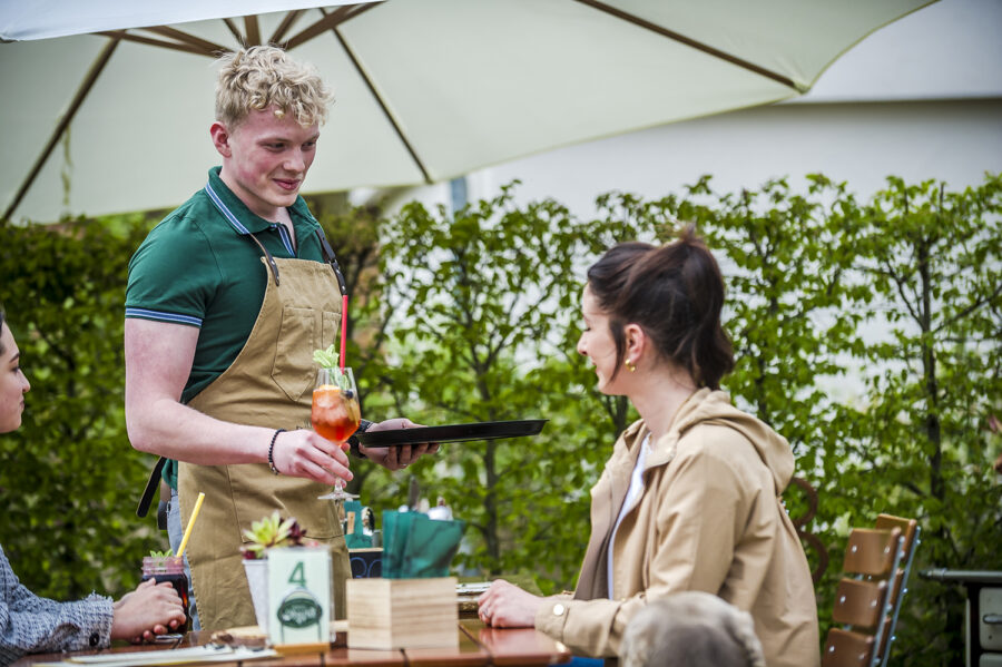 Gäste im Biergarten in Interaktion mit dem Service