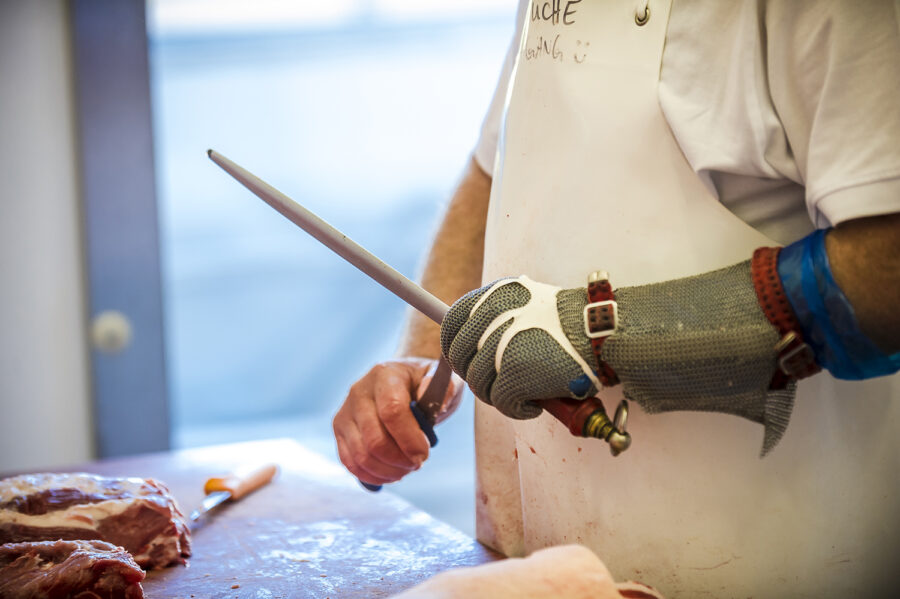 Zerlegung in der Metzgerei - Mitarbeiter beim Schleifen der Messer