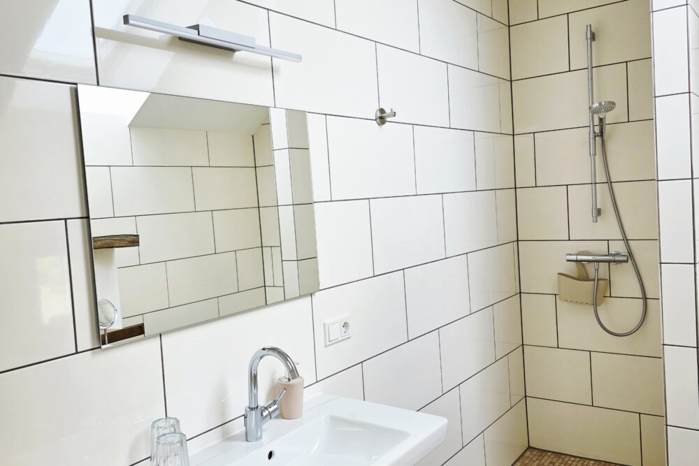 Badezimmer des Hotelzimmers Gänseblümchen, Blick auf Waschbecken mit Spiegel und begehbare, offene Dusche