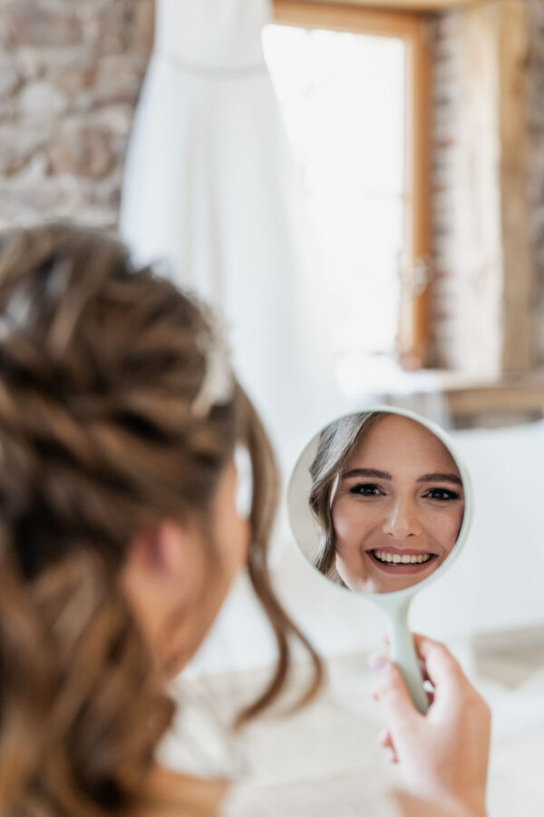 lächelnde Braut im Spiegel beim Getting Ready